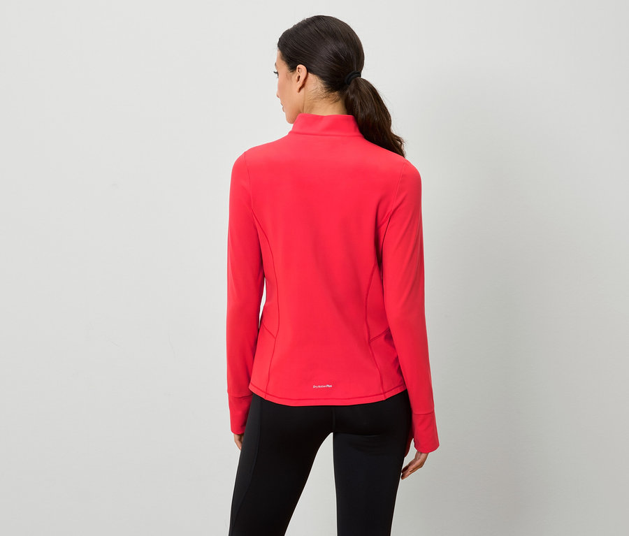 Arkası dönük bir kadın kırmızı fermuarlı polar ve siyah tayt giyiyor.