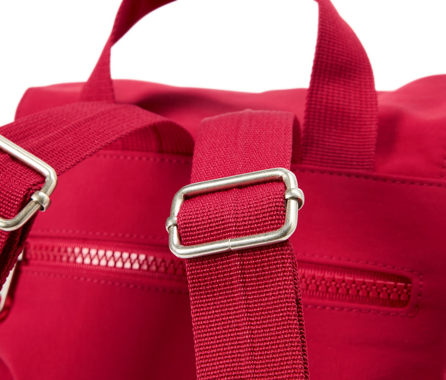 Askılarında gümüş tokalar bulunan kırmızı bir sırt çantasının yakın çekimi.