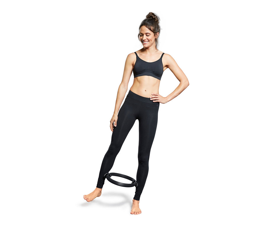 Kadın bacaklarının arasında siyah bir Pilates Halkası ile egzersiz yapıyor.