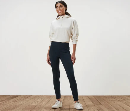 Ahşap zeminde duran bir kadın Kalın Tayt ve sweatshirt giyiyor.