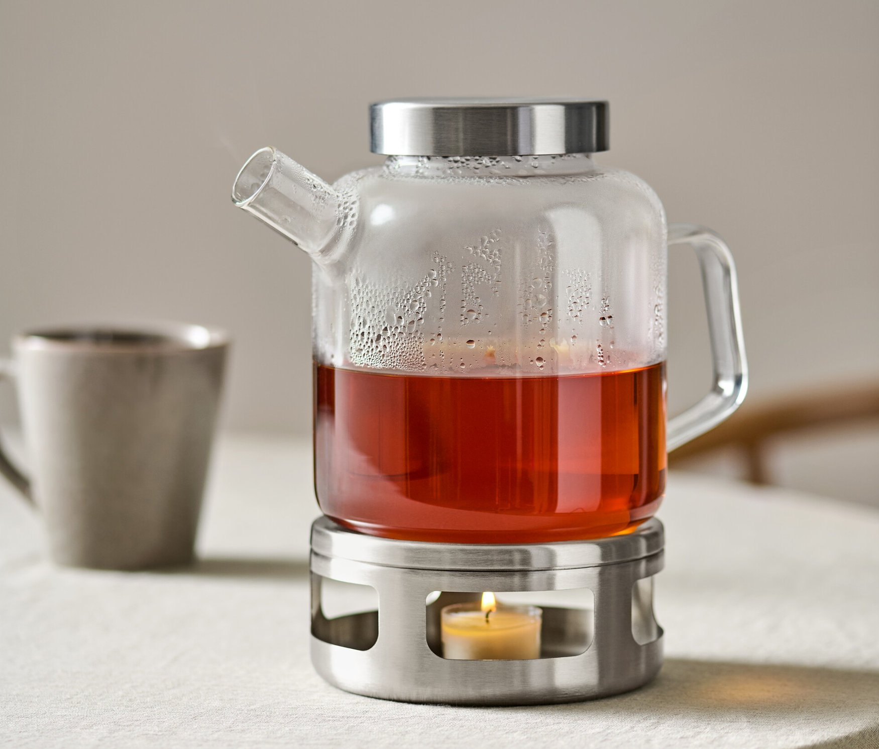 Çaylı cam demlik, yanan mumlu ısıtıcı üzerinde duruyor.