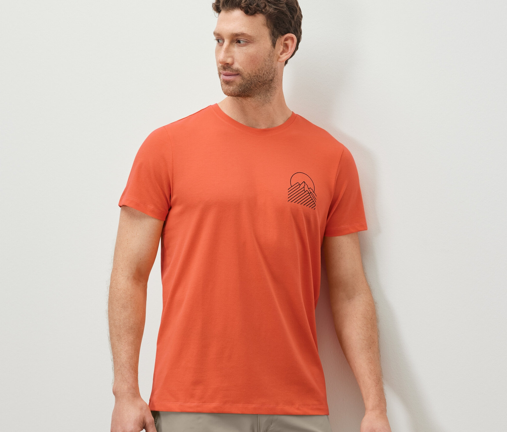 Adam turuncu, baskılı tişört giyiyor.