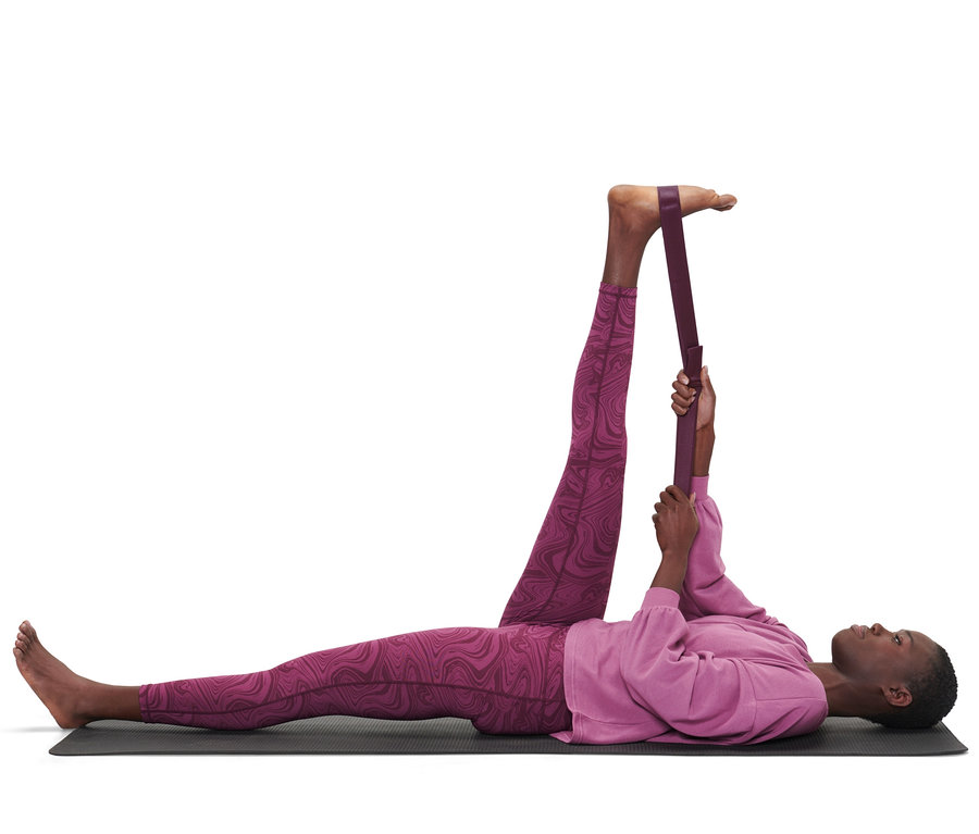 Bir kadın yerde yatıyor ve 2'si 1 Arada Yoga Kemeri ile bacağını esnetiyor.