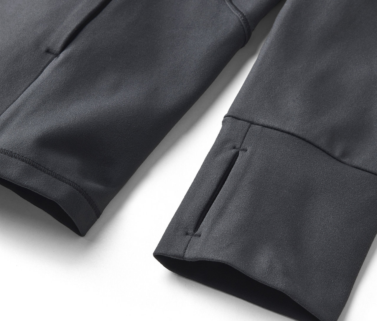 Manşetlerinde başparmak delikleri ve yan cebi olan gri bir sweatshirt'ün yakın çekim detayı.