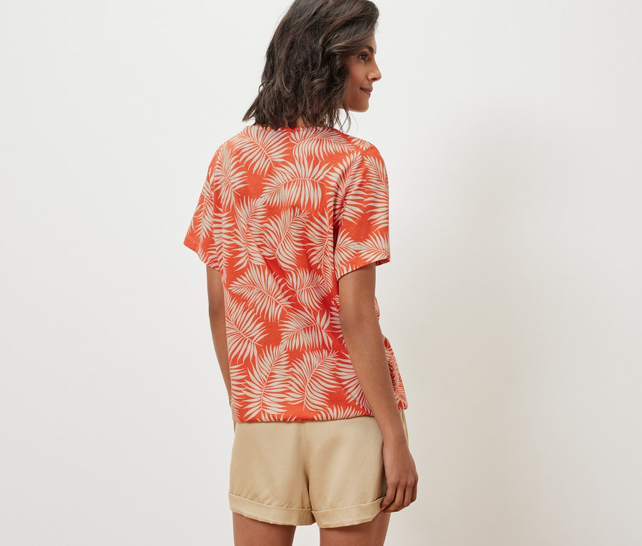 Kadın desenli bluz ve şort giyiyor.