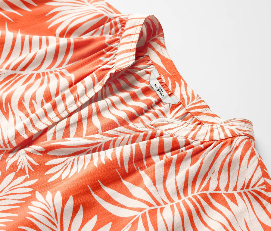 Yaprak desenli turuncu kısa kollu bluzun yakın çekimi.