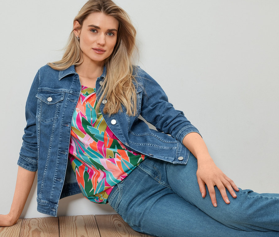 Kadın yerde oturuyor ve kot ceket giyiyor.