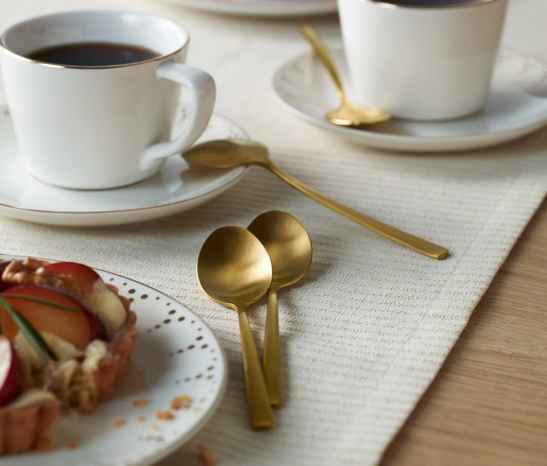 Bir masanın üzerinde iki fincan kahve ve iki tabak kek. Masanın üzerinde Çatal Bıçak Kaşık Seti, 4 Adet Kahve Kaşığı bulunmaktadır.