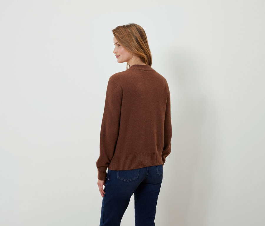 Kahverengi saçlı, kahverengi kazaklı ve koyu mavi kot pantolonlu bir kadının arkadan görünüşü.