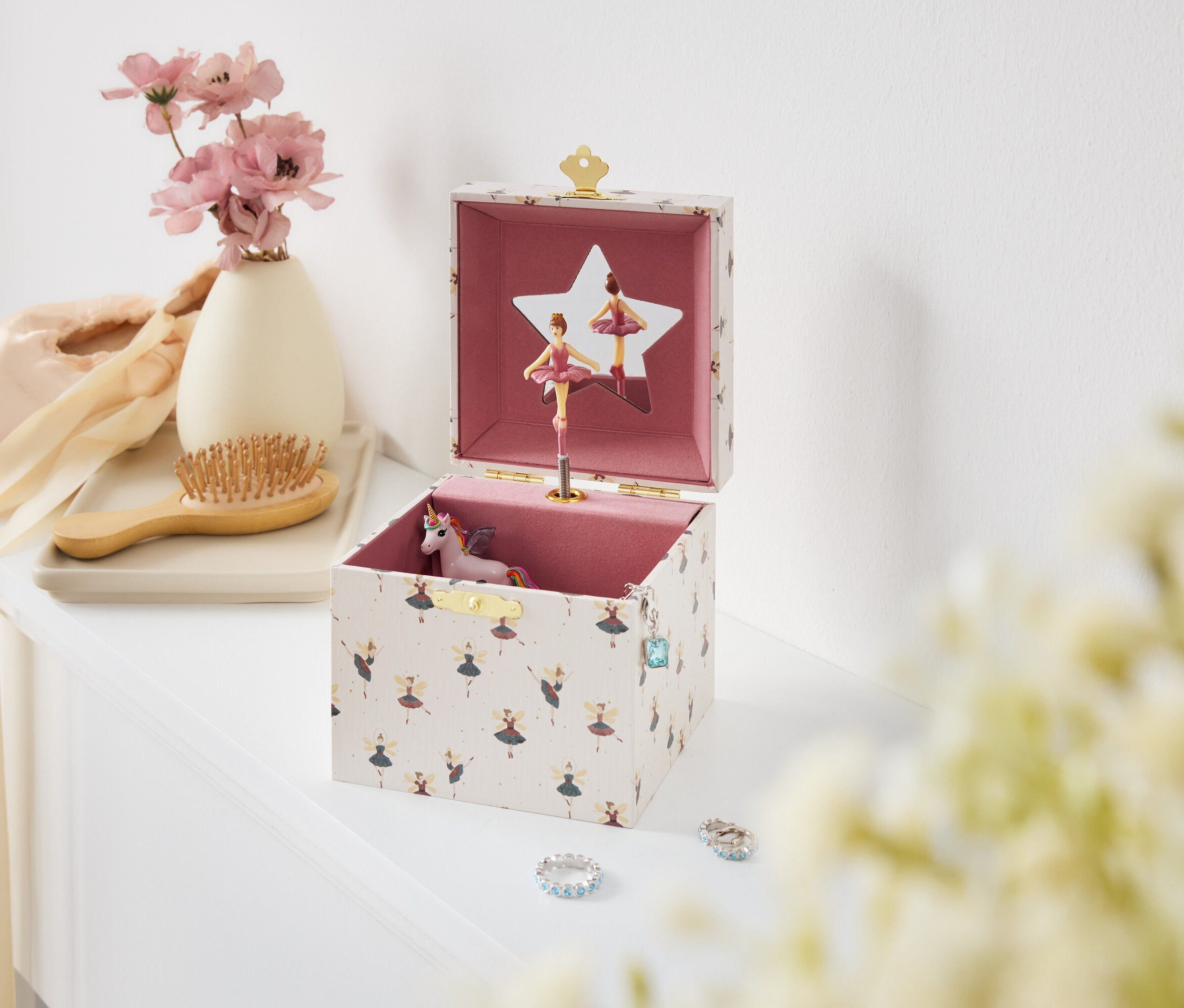 Beyaz bir masanın üzerinde balerinler ve tek boynuzlu at bulunan açık bir müzik kutusu.