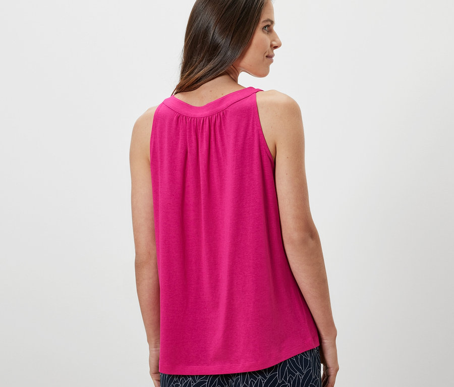 Kadın omzunun üzerinden bakıyor ve pembe bir üst giyiyor.