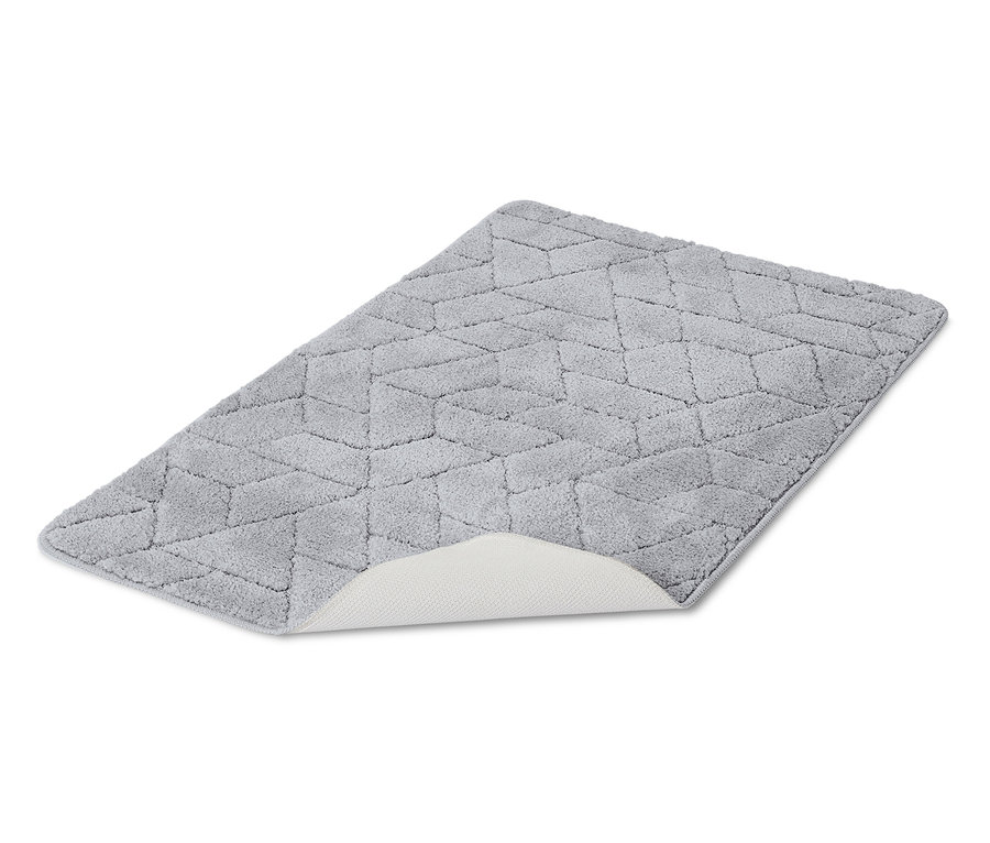 Geometrik desenli gri bir banyo paspası beyaz bir arka plan üzerinde duruyor.