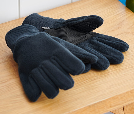 Çocuk polar eldivenleri, bir sırt çantası ve kaykayın yanında ahşap bir bankta duruyor.