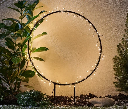 Metal LED Outdoor Halka bitkilerin arasında duruyor.