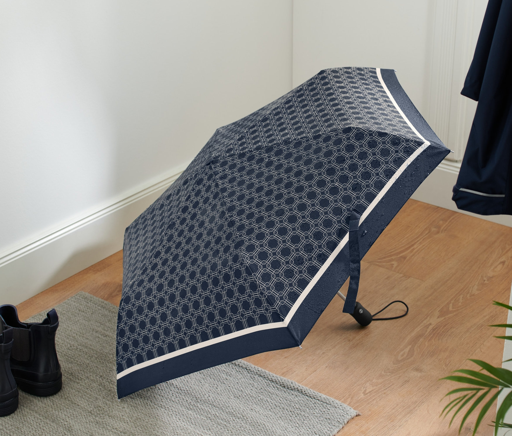 Geometrik desenli açık otomatik cep şemsiyesi, yerde botların yanında duruyor.