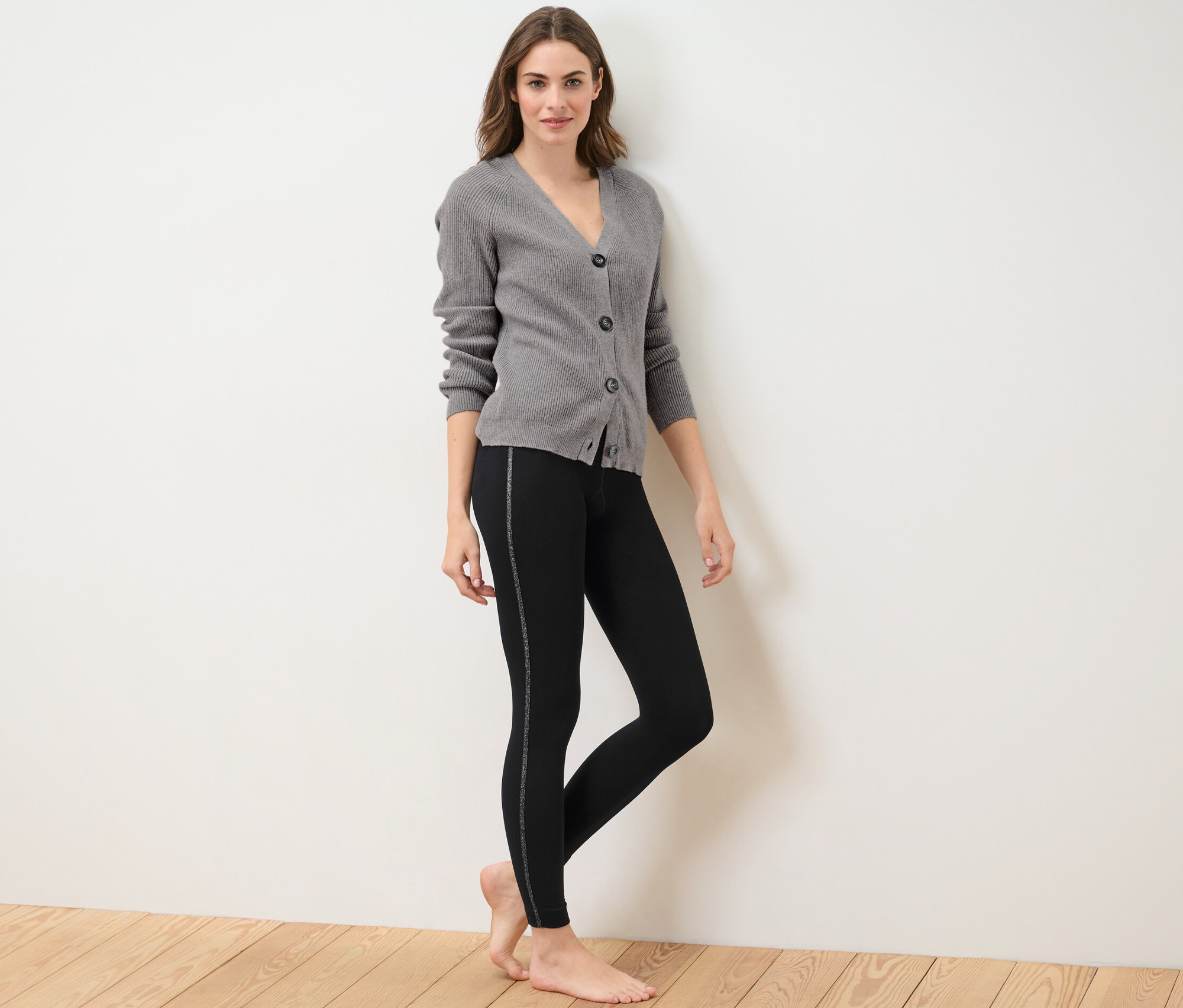 Kadın simli bantlı termal tayt ve gri hırka ile poz veriyor.