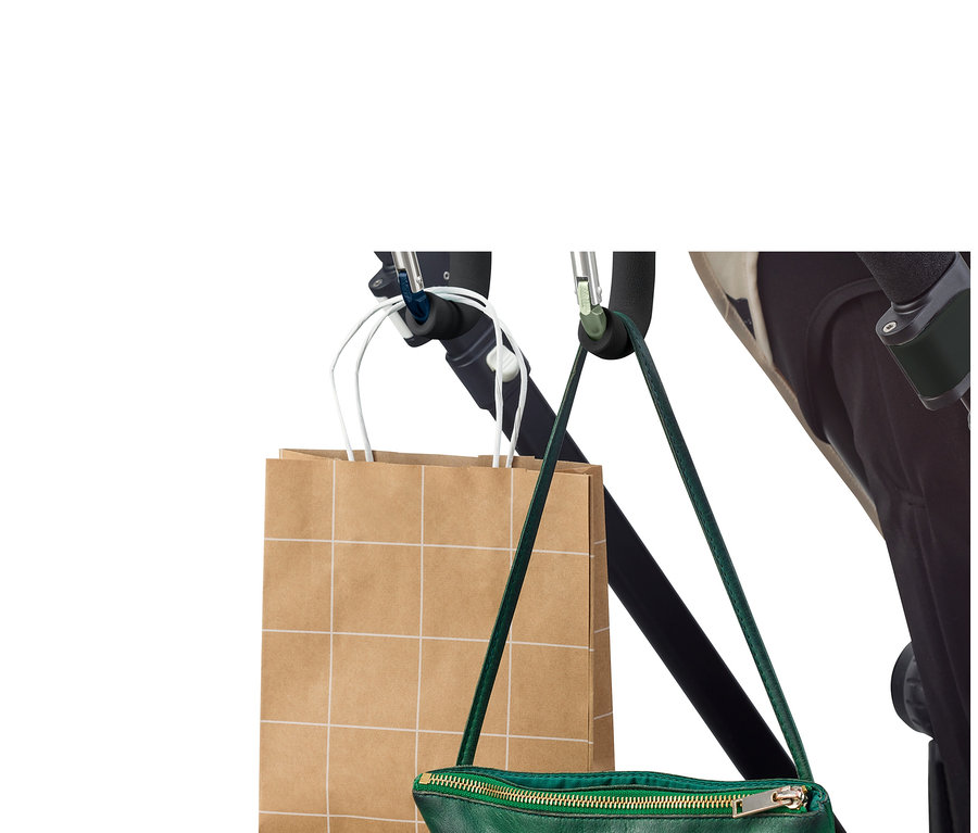 Bir alışveriş çantası ve yeşil bir el çantası, 2 adet XXL karabina kancasıyla bir bebek arabasına asılıyor.