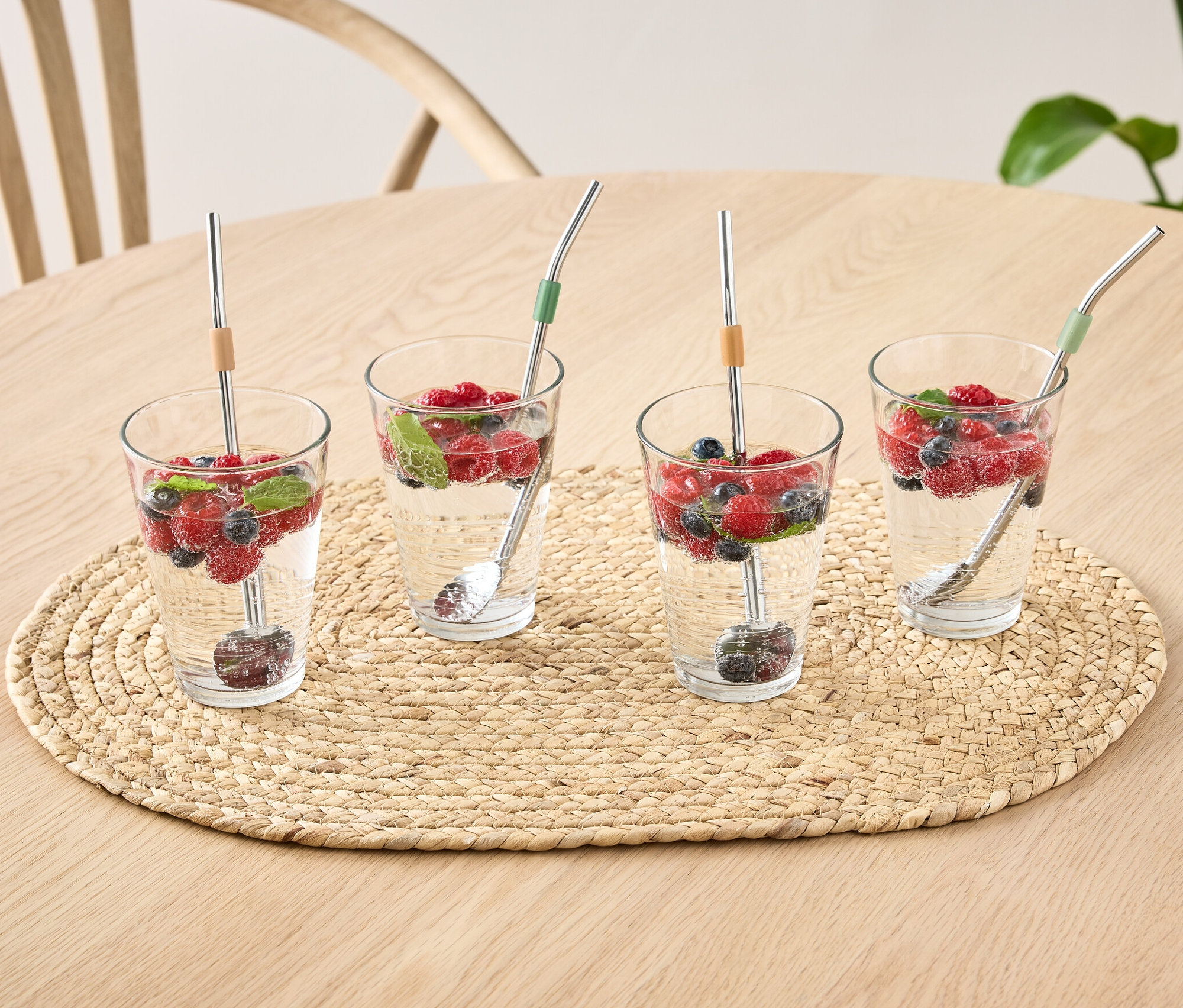 Masanın üzerinde su, meyve ve 4 Adet Kaşık bulunan dört bardak.