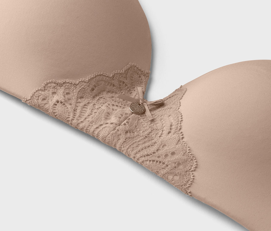 Dantel detaylı ve küçük dekoratif düğmeli bej rengi sütyenin yakın çekimi.