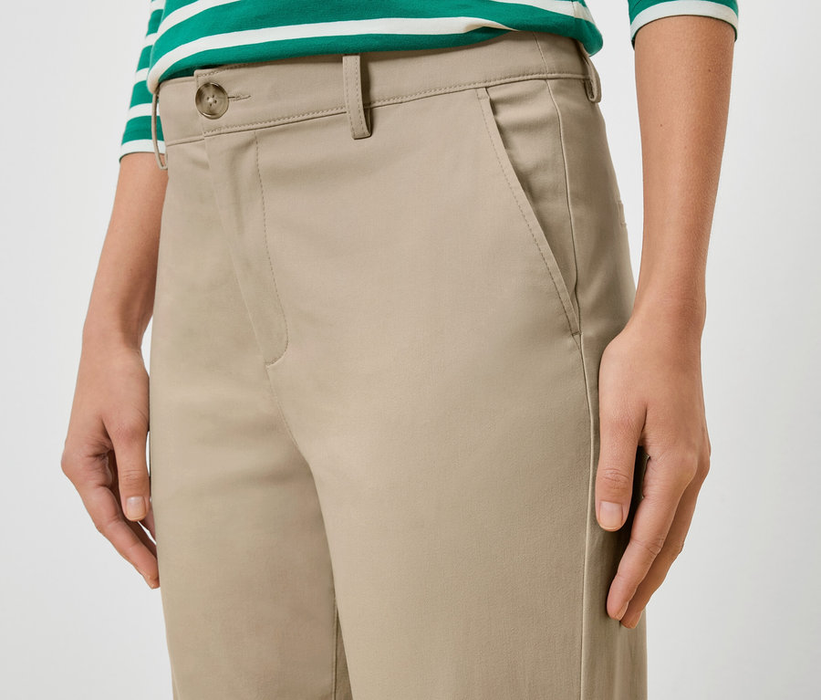 Bej rengi pantolon ve yeşil-beyaz çizgili üst giyen bir kadının yakın çekimi.