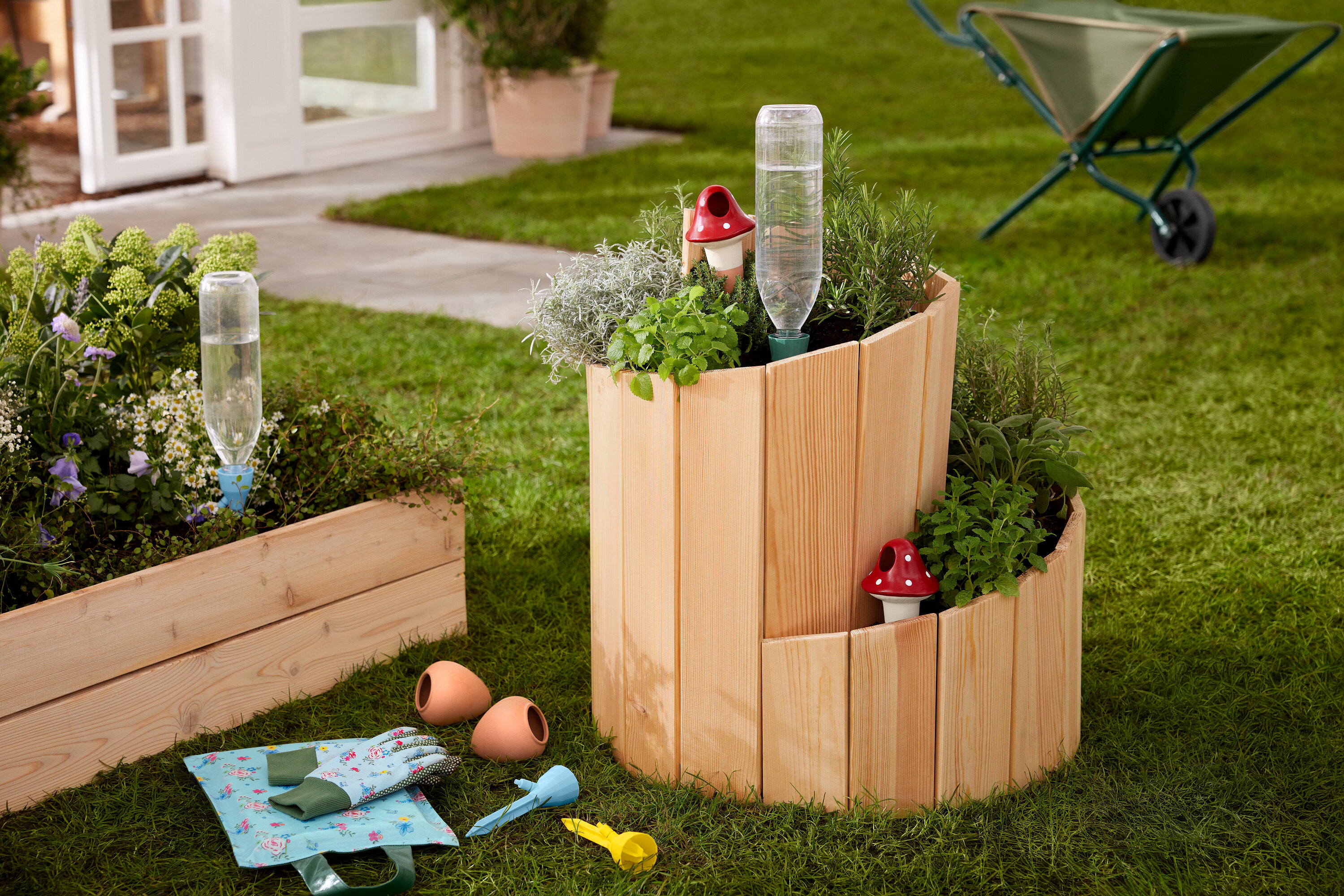 Çim üzerinde, otlar ve sebzelerle dikilmiş ahşap bir yükseltilmiş tarh »Salyangoz« duruyor.