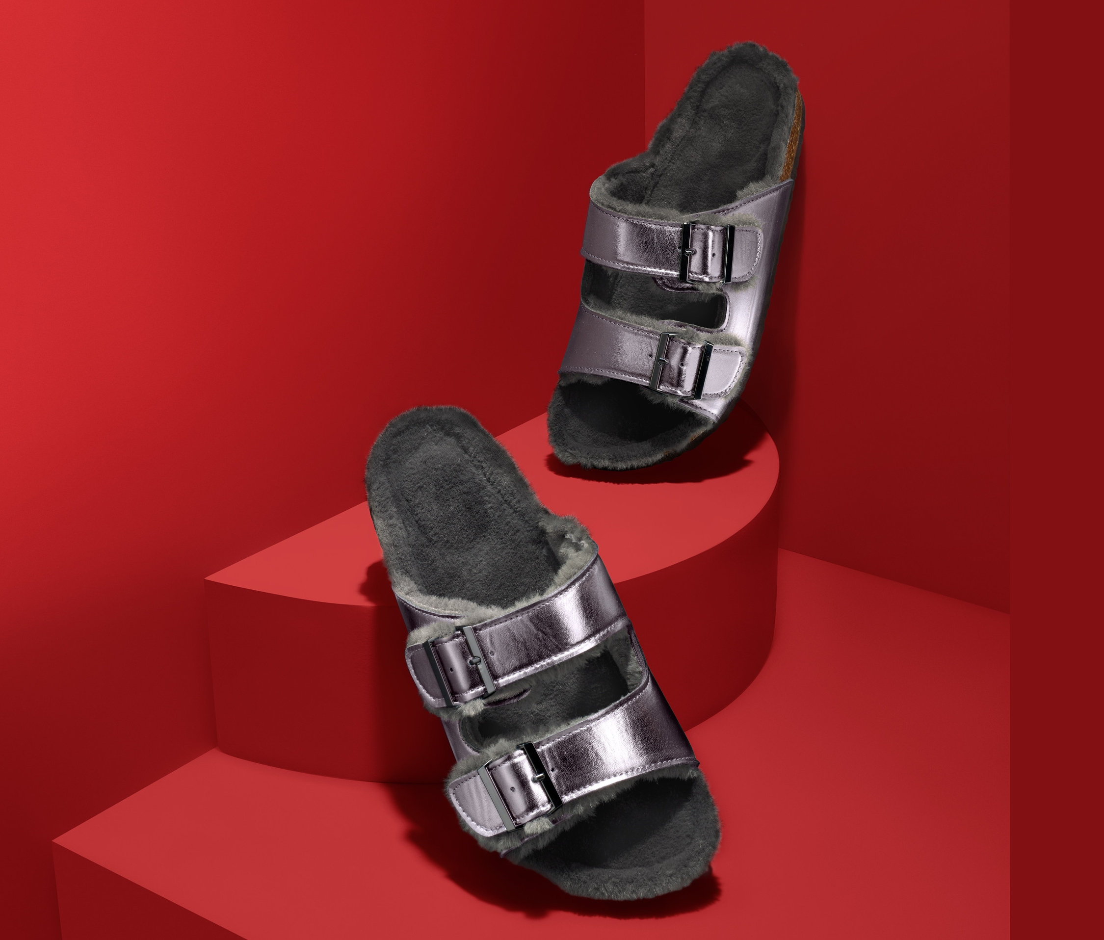 Kırmızı bir arka plan üzerinde iki gümüş renkli, astarlı ev terliği.