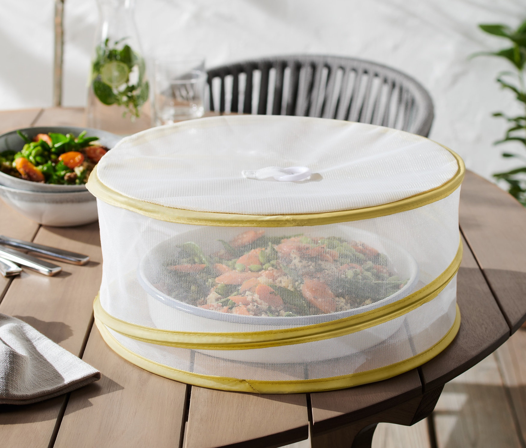 Ahşap bir masanın üzerinde, katlanabilir koruyucu kapakla örtülmüş bir yemek duruyor.