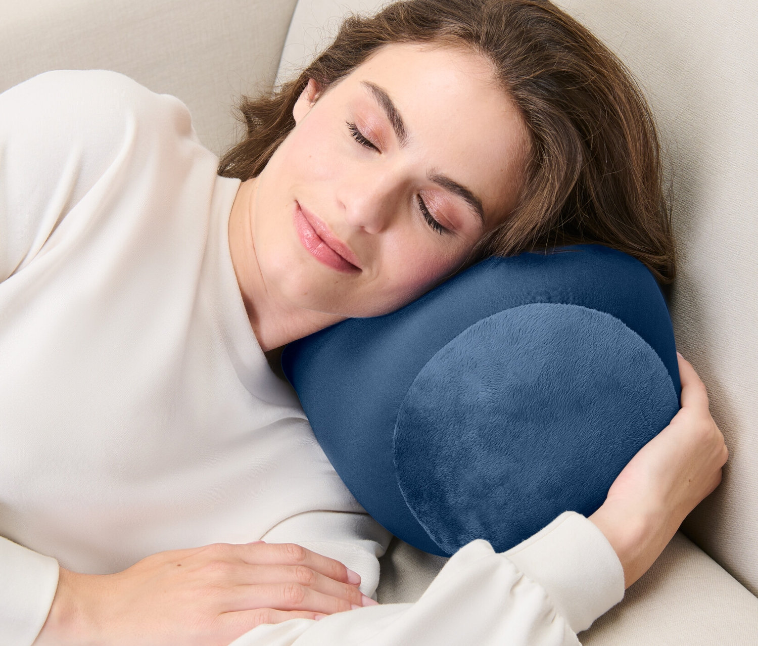 Kadın bej renkli bir koltukta Rahatlama Yastığı ile uyuyor.