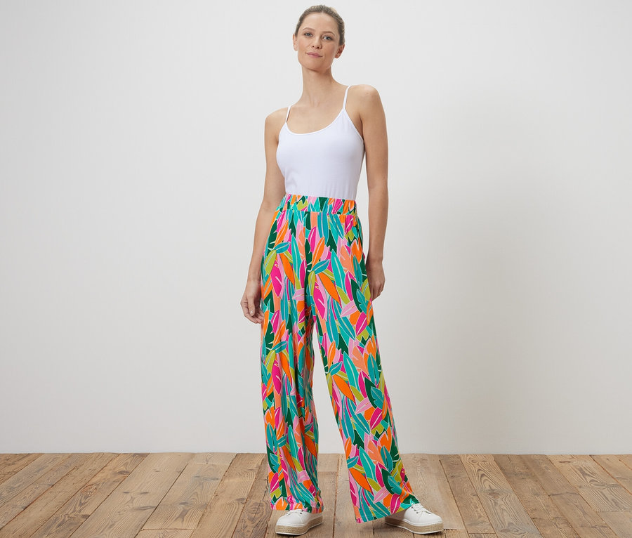 Ayakta duran bir kadın baskılı, çok renkli palazzo pantolon giyiyor.