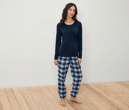 Kadın lacivert, uzun kollu bir pijama üstü ve ekose pantolon giyiyor.