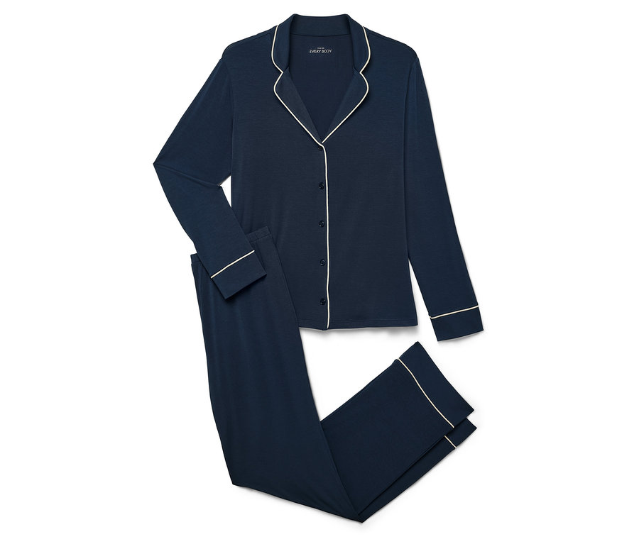 Beyaz bir arka planda, uzun kollu üstü ve pantolonu beyaz şeritli, lacivert renkli pijama.