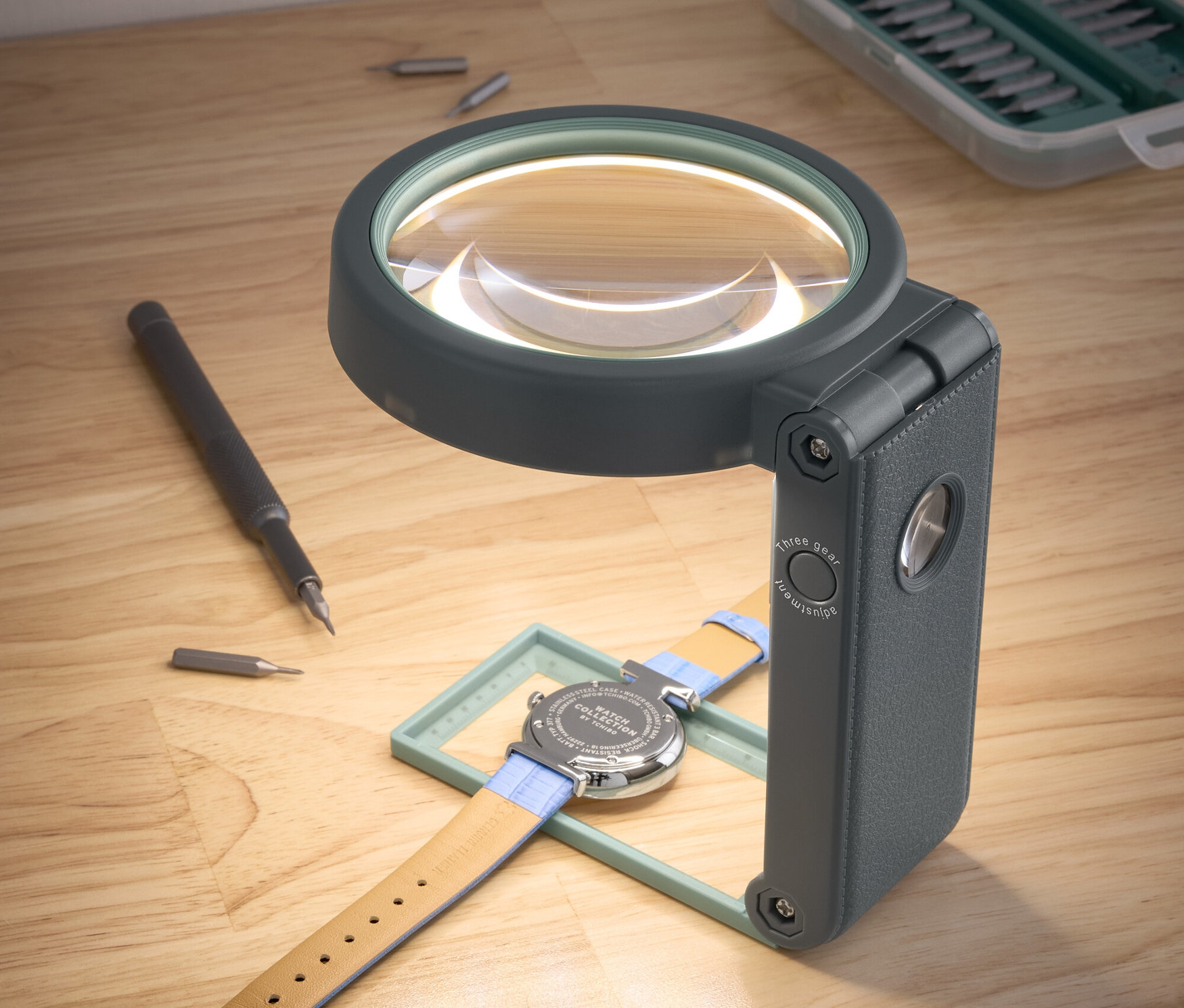 Bir saat, standlı bir LED çalışma büyütecinin altında duruyor.