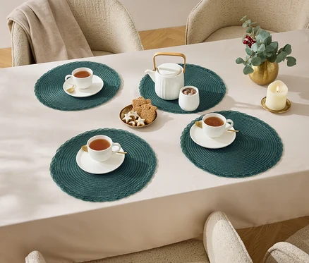 Masa üzerinde dört bardak çay, masa örtüsü, çaydanlık, şekerlik, kurabiye ve mum.