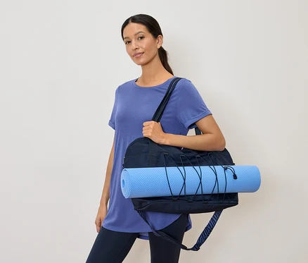 Lacivert spor çantası ve açık mavi yoga matı olan kadın