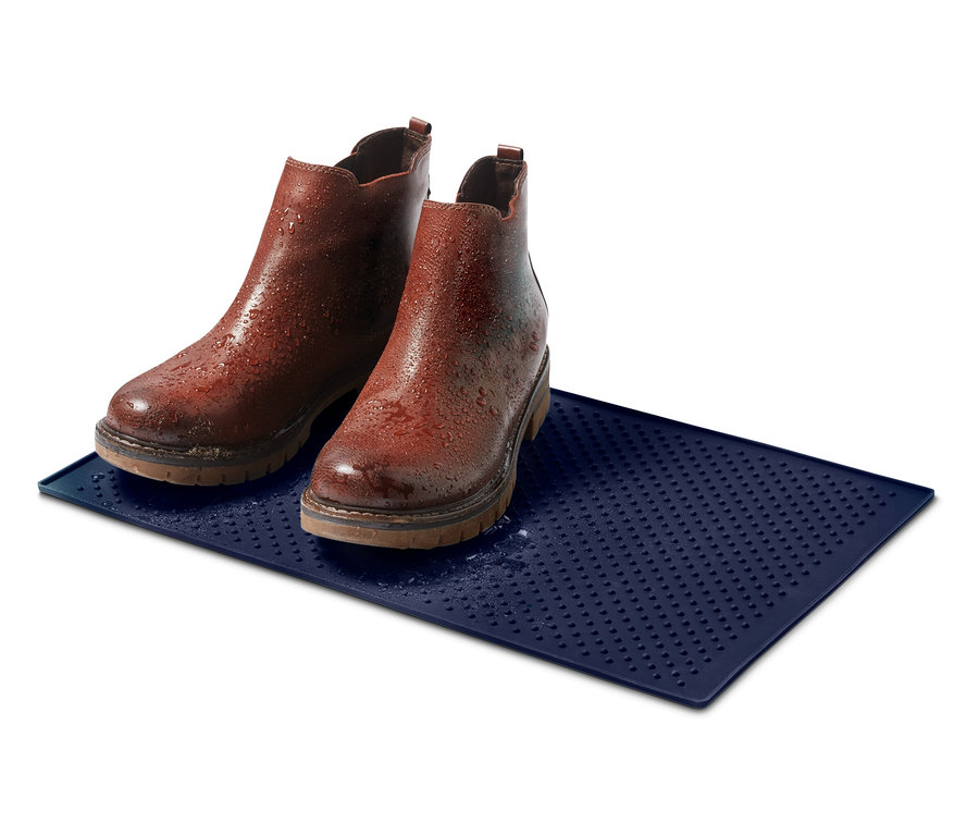 Su damlaları olan mavi bir mat üzerinde duran iki adet kahverengi deri ayak bileği botu.