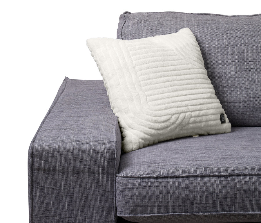 Gri bir kanepenin üzerinde beyaz renkli, pille çalışan, yaklaşık 45 x 45 cm boyutlarında ısıtmalı dekoratif bir yastık bulunmaktadır.