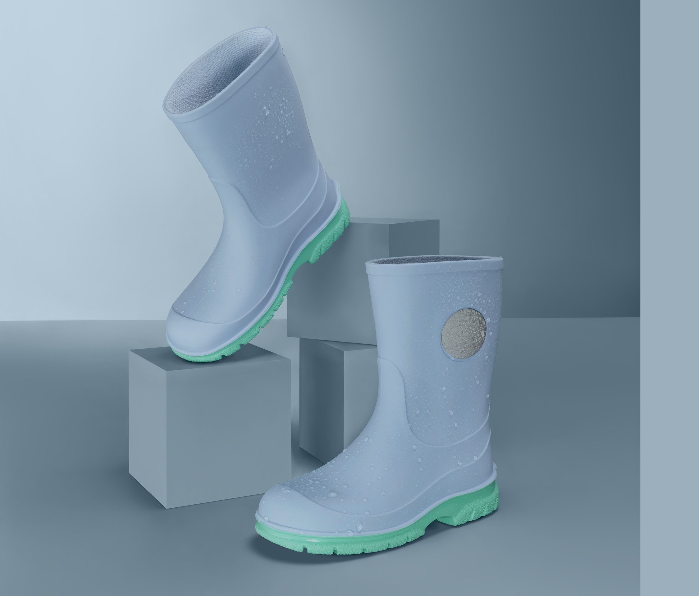 Gri küpler üzerinde limon yeşili tabanlı iki açık mavi yağmur çizmesi.