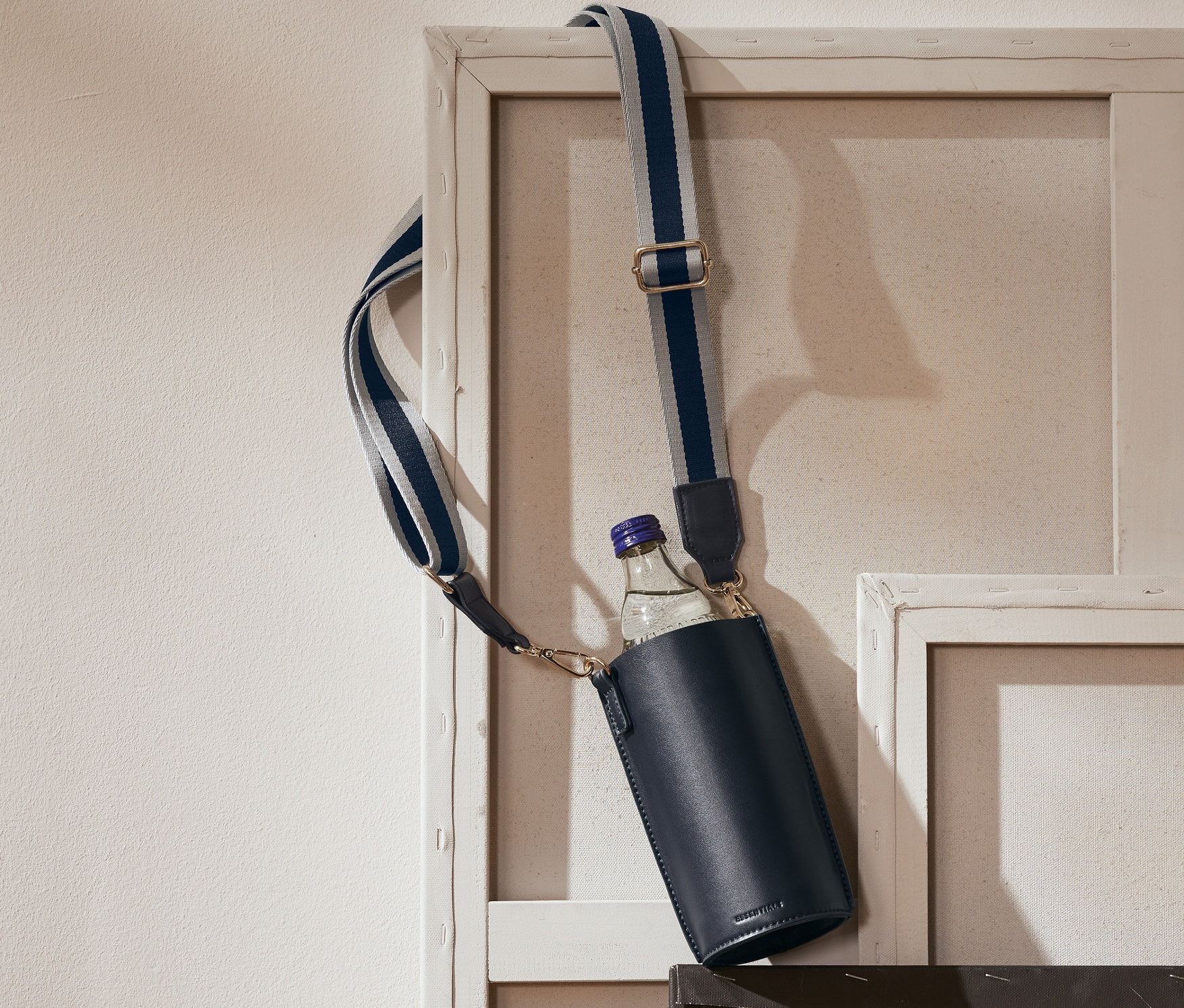 Lacivert bir Şişe Çantası bir resim çerçevesinde asılı duruyor.