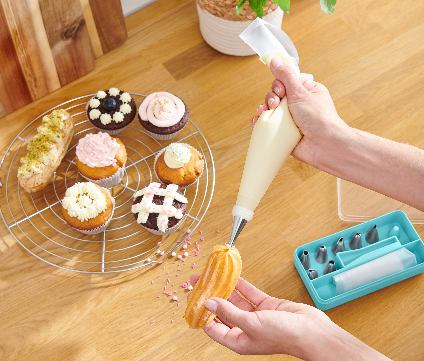 Bir kişi, Krema Sıkma Uçları Seti ile bir ekler tatlısını süslüyor.