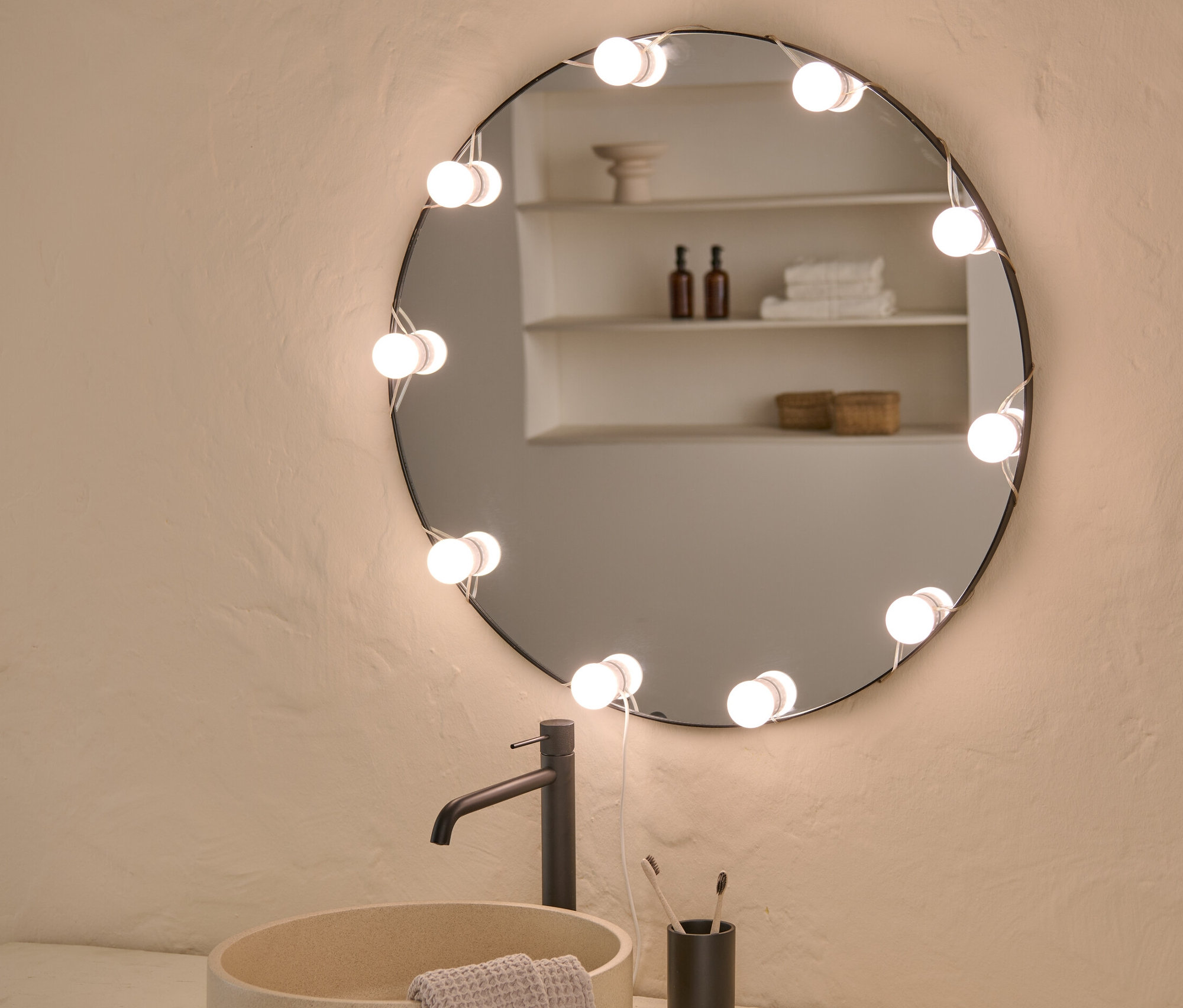 Lavabo, armatür ve LED'li USB Işık Zinciri olan yuvarlak aynalı banyo.