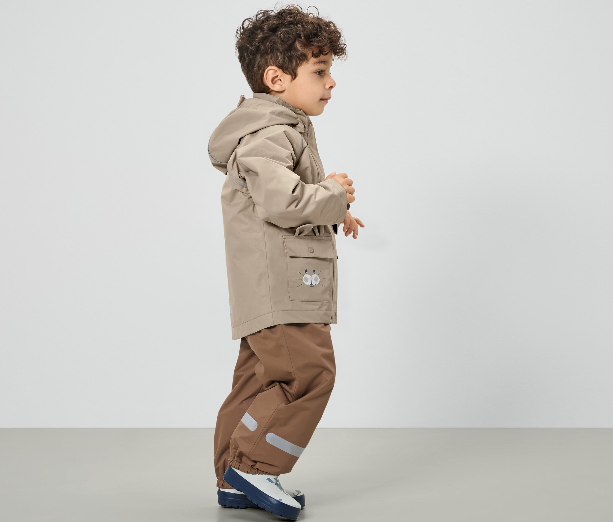 Kahverengi çocuk yağmurluğu giyen erkek çocuk.