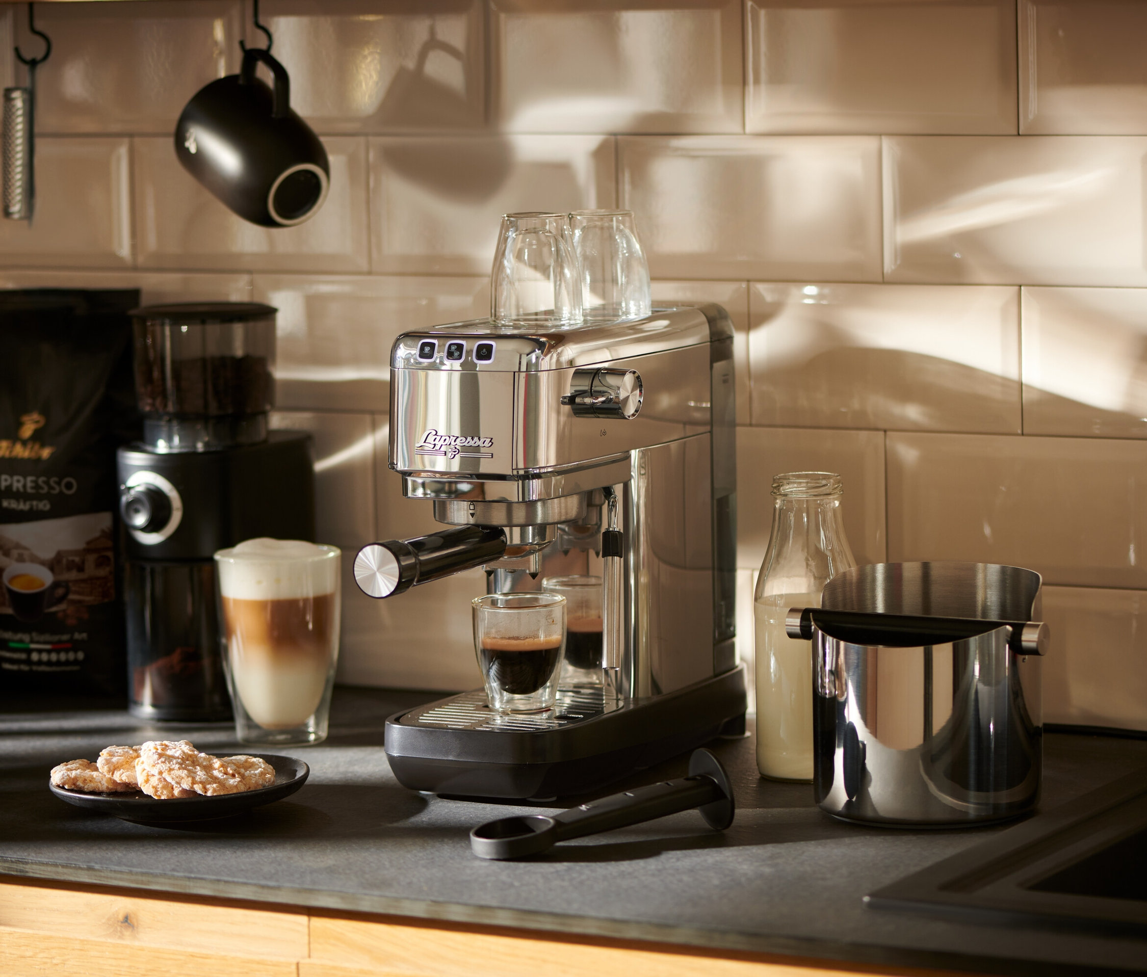 Tezgâhta duran gümüş renkli »Lapressa« Portafiltre Makinesi, bir bardağa espresso hazırlıyor.