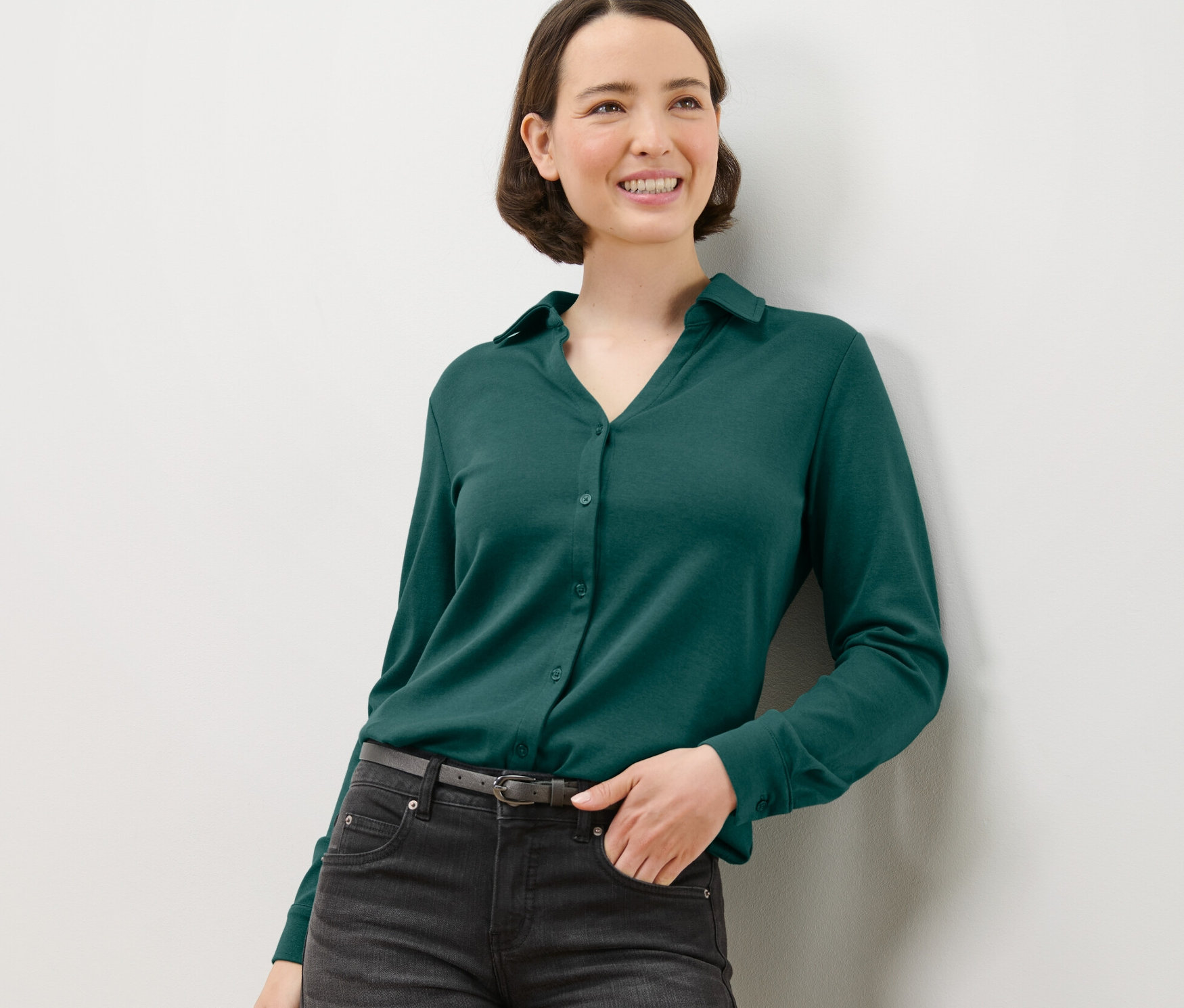 Kadın, yeşil düğmeli bluz ile poz veriyor.