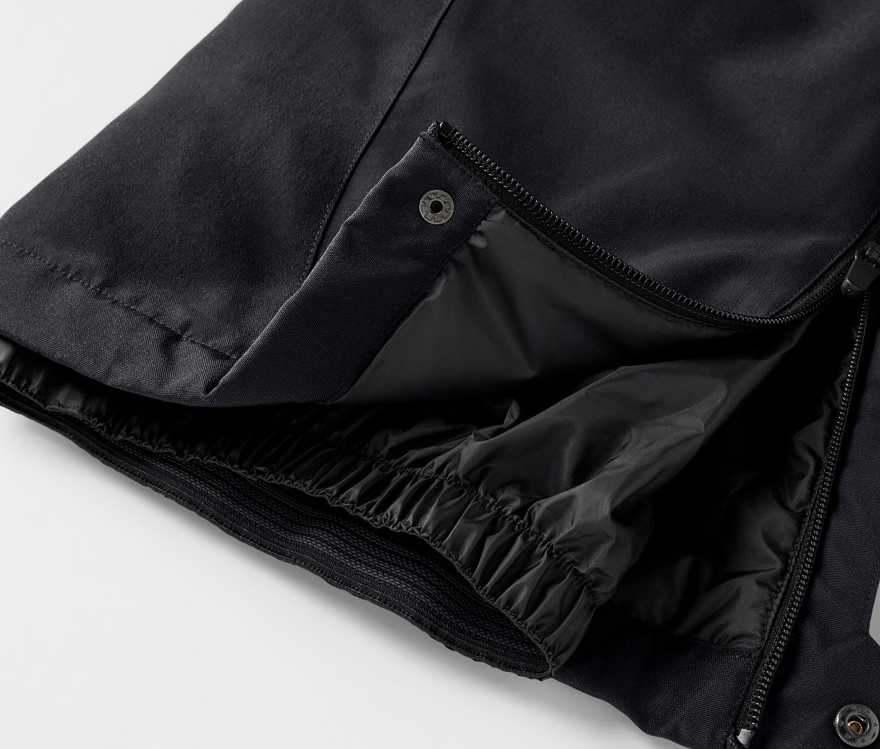 Açık fermuarı ve çıtçıtı olan siyah bir pantolonun detayı.