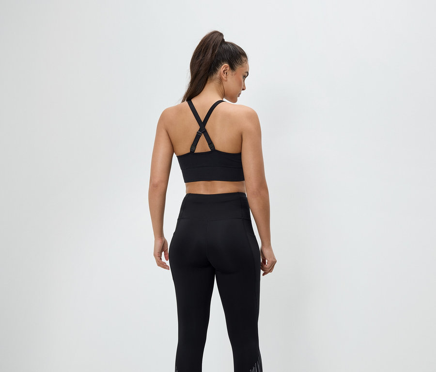 Siyah spor giyiminde, spor sütyeni ve tayttan oluşan bir kadının arka görünümü.