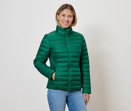 Kadın yeşil şişme mont ve kot pantolon giyiyor.