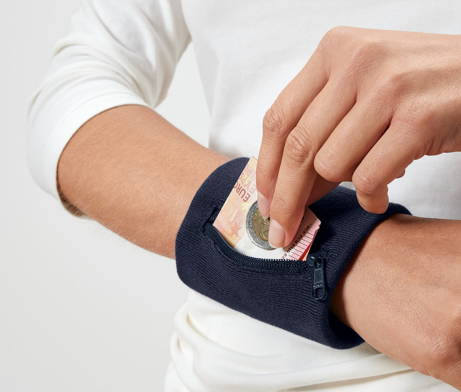 Bir kişi lacivert bir bileklik cebine bir Euro madeni para koyuyor.