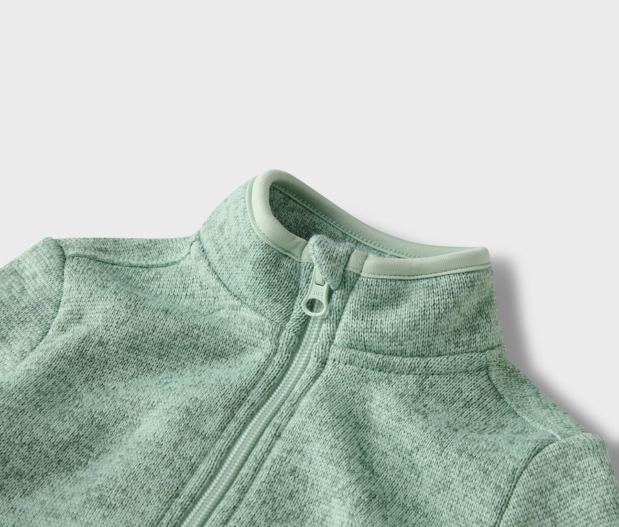 Açık yeşil renkli, fermuarlı bir polar sweatshirt'ün yakın çekimi.