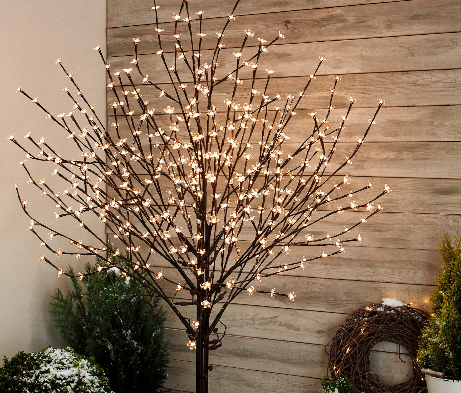 Çiçekli LED Ağaç bitkiler arasında dışarıda duruyor.