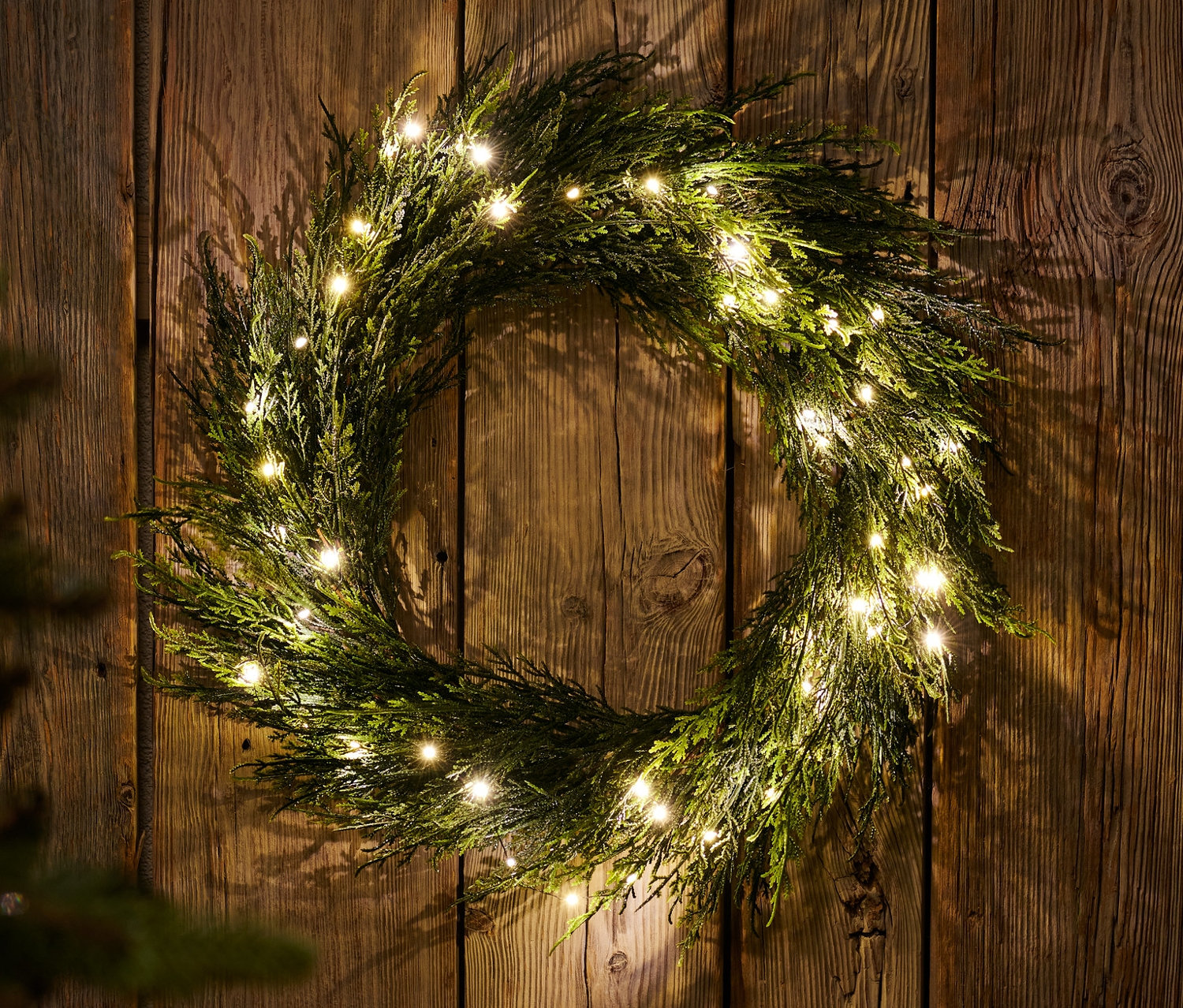 Ahşap bir duvarda LED'li dekoratif çelenk asılı duruyor.
